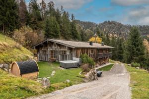 ein Haus auf einem Hügel mit einer Straße davor in der Unterkunft Luxury old wood mountain chalet in a sunny secluded location with gym, sauna & whirlpool in Scheffau am Wilden Kaiser