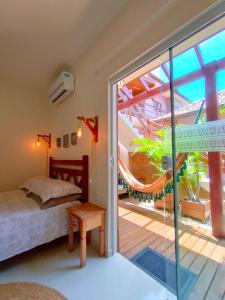 a bedroom with a bed and a sliding glass door at Origin Acomodações in Guarda do Embaú