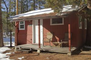 una casita roja con porche y silla en Silver Pines Lodge en Idyllwild