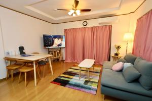 uma sala de estar com um sofá e uma mesa em Guest House Kubo Homes Matsu em Osaka