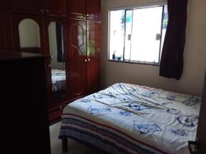 a bedroom with a bed and a dresser and a window at Casa em São Thomé das Letras in São Thomé das Letras