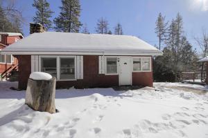a house is covered in snow with a tree stump at Silver Pines Lodge in Idyllwild