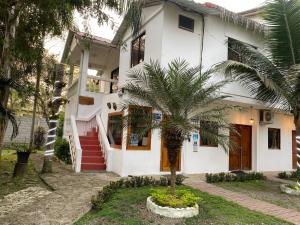 a white house with a palm tree in front of it at Palmendros Hosteria in Montañita