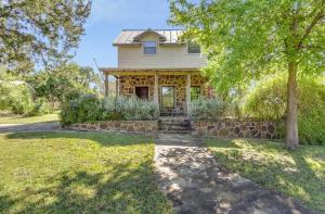 a house with a stone wall and a tree at Last Outpost Bandera Ranch House in Bandera