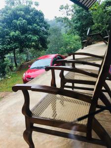a bench sitting on a porch with a car in the background at Little wood villa Doluwa in Kandy