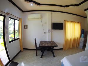 una camera con tavolo, televisore e letto di Villa Consolacion Resort a General Luna
