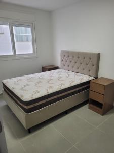 a bedroom with a bed and a nightstand next to a window at Lindo apartamento 1 quarto in Capão da Canoa