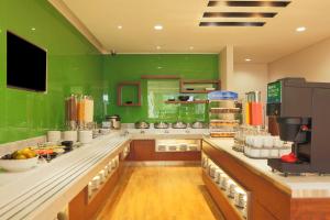 uma grande cozinha com paredes verdes e balcões de madeira em Holiday Inn Express Semarang Simpang Lima, an IHG Hotel em Semarang