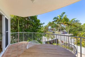 a balcony with a table and chairs and palm trees at Rivershores in Noosaville