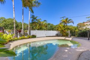 a swimming pool in a yard with palm trees at Rivershores in Noosaville