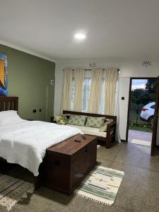 a bedroom with a bed and a couch and a window at Koselig Homes in Nanyuki