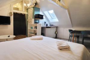a bedroom with a large white bed and a kitchen at La Cabane - Petit studio mansardé - Plage 50m - Rue gratuite in Saint Malo