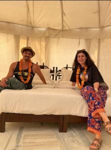 a man and a woman sitting on a bed at Journey Desert Camp Jaisalmer in Jaisalmer