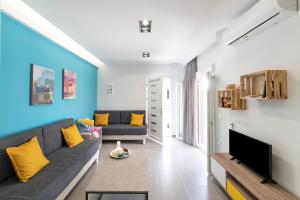 Chania Design Suites في مدينة خانيا: غرفة معيشة مع أريكة وتلفزيون