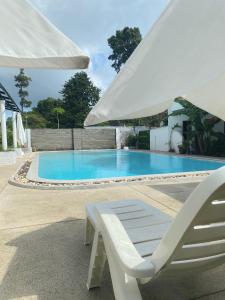 a white chair and an umbrella next to a swimming pool at Chaweng Residence in Chaweng