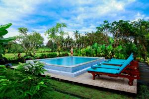 a swimming pool with two blue lounge chairs next to it at The Dukuh Retreat in Tabanan