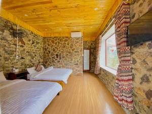 two beds in a room with a stone wall at Lan Rừng Homestay in Lũng Niêo