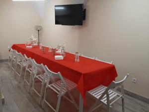 a long red table with chairs and a television at La Morada de Moret in Cáceres