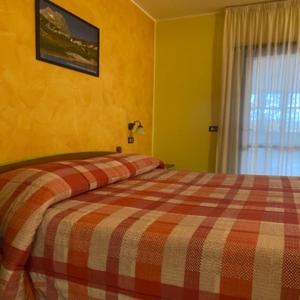 een slaapkamer met een bed met een geruite deken bij Hotel Giampy in Assergi