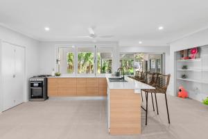 a kitchen with white walls and wooden cabinets and appliances at Sandpipers Beach House in Palm Cove