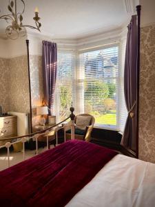 Schlafzimmer mit einem Bett, einem Schreibtisch und einem Fenster in der Unterkunft Glenville House - Adults Only - Incl FREE off-site health club with swimming pool, hot tub, sauna & steam room in Windermere