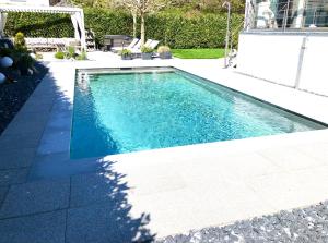 a swimming pool with blue water in a yard at Sunny Way Home Accommodation & Spa in Weite