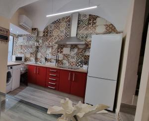 a kitchen with red cabinets and a white refrigerator at La Morada de Moret in Cáceres
