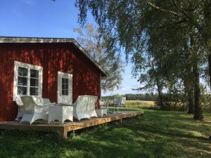 a red barn with white chairs on a deck at Karaby Gård, Country Living in Kristinehamn