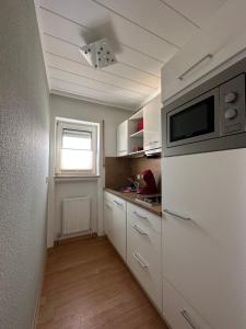 eine Küche mit einem Kühlschrank und einer Mikrowelle in der Unterkunft FeWo-City in Gießen