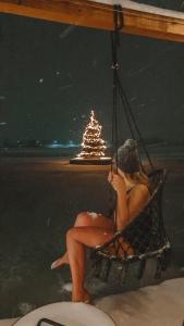 een vrouw die 's nachts in een schommel op een strand zit bij Costa del Kryspi Całoroczne Domy na Wodzie in Cholerzyn