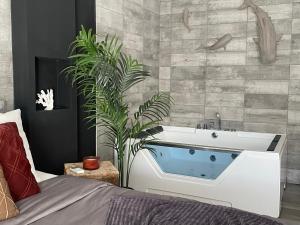 un bagno con vasca e una pianta accanto a un letto di Superbe appartement avec balnéo. a Saint-Cyprien Altre 21 foto