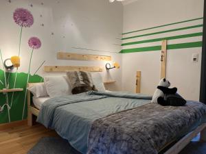 um quarto com um urso panda sentado numa cama em L'attente détente à 200 m du parc " Pairi Daiza " em Brugelette