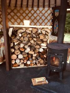 a pile of fire wood next to a stove at Mongolian yurt sleeping 2+2 with outdoor space in Llanbrynmair