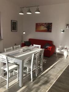een witte eettafel met witte stoelen en een rode bank bij Appartamento Trilocale “Il Regio” in Montescudaio