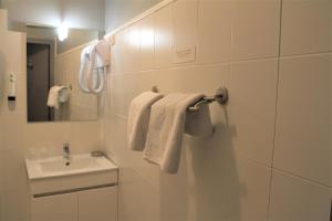 La salle de bains est pourvue d'un lavabo, d'un miroir et de serviettes. dans l'établissement Hôtel Pontet, à Beynac-et-Cazenac