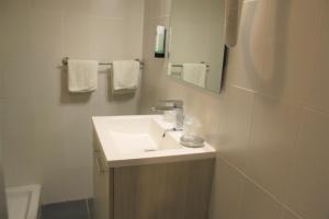 een witte badkamer met een wastafel en een spiegel bij Hôtel Pontet in Beynac-et-Cazenac