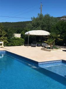 - une piscine avec une table, des chaises et un parasol dans l'établissement Mas de guffiage, à Bollène