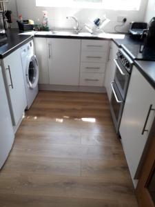 a kitchen with white appliances and a wooden floor at Beautiful Private Rooms in London Central Willesden Green in London