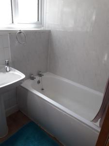 a white bathroom with a tub and a sink at Beautiful Private Rooms in London Central Willesden Green in London