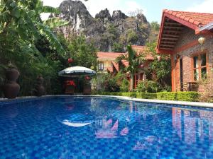 a large swimming pool with a mountain in the background at Tam Coc Friendly Homestay in Ninh Binh