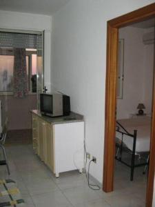 ein Wohnzimmer mit einem TV auf einer Kommode mit einem Bett in der Unterkunft Bella Otranto in Otranto