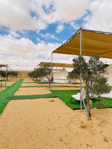 uma fileira de tendas com um relvado verde e árvores em נירוונה במדבר em Be'er Milka