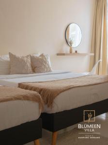 two beds in a bedroom with a mirror on the wall at Blumeen Villa 2 in Kuala Terengganu