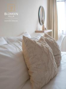 a bed with white sheets and pillows on it at Blumeen Villa 2 in Kuala Terengganu