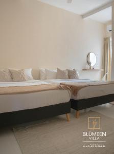 a bedroom with two beds and a mirror on the wall at Blumeen Villa 2 in Kuala Terengganu