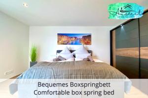 a bedroom with a bed with a painting on the wall at Auszeit Apartment SMILE in Friedrichshafen +19 photos