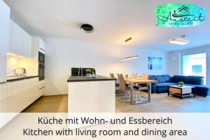 una cucina con soggiorno e zona pranzo di Auszeit Apartment SMILE am Uferpark - nur 100 m bis zum Bodensee, direkt am Bodenseeradweg, 2 Schlafzimmer, 2 Sonnenbalkone, schnelles WLAN, kostenloser Tiefgaragenstellplatz, für bis zu 4 Personen a Friedrichshafen