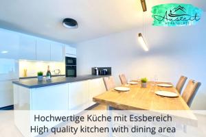 cocina con mesa de madera con sillas y barra en Auszeit Apartment SMILE am Uferpark - nur 100 m bis zum Bodensee, direkt am Bodenseeradweg, 2 Schlafzimmer, 2 Sonnenbalkone, schnelles WLAN, kostenloser Tiefgaragenstellplatz, für bis zu 4 Personen, en Friedrichshafen