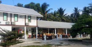 ein weißes Gebäude mit Bäumen im Hintergrund in der Unterkunft Fikri Wetland Guesthouse & Resort 