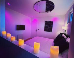 Un dormitorio con una cama con luces moradas. en Léa Room - Gîte Romantique - Jacuzzi en Bourguébus